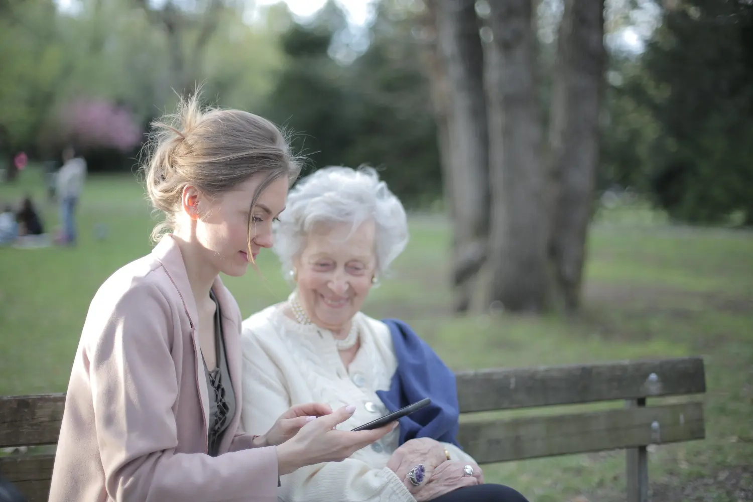 A younger woman is showing a mobile phone to an older woman.