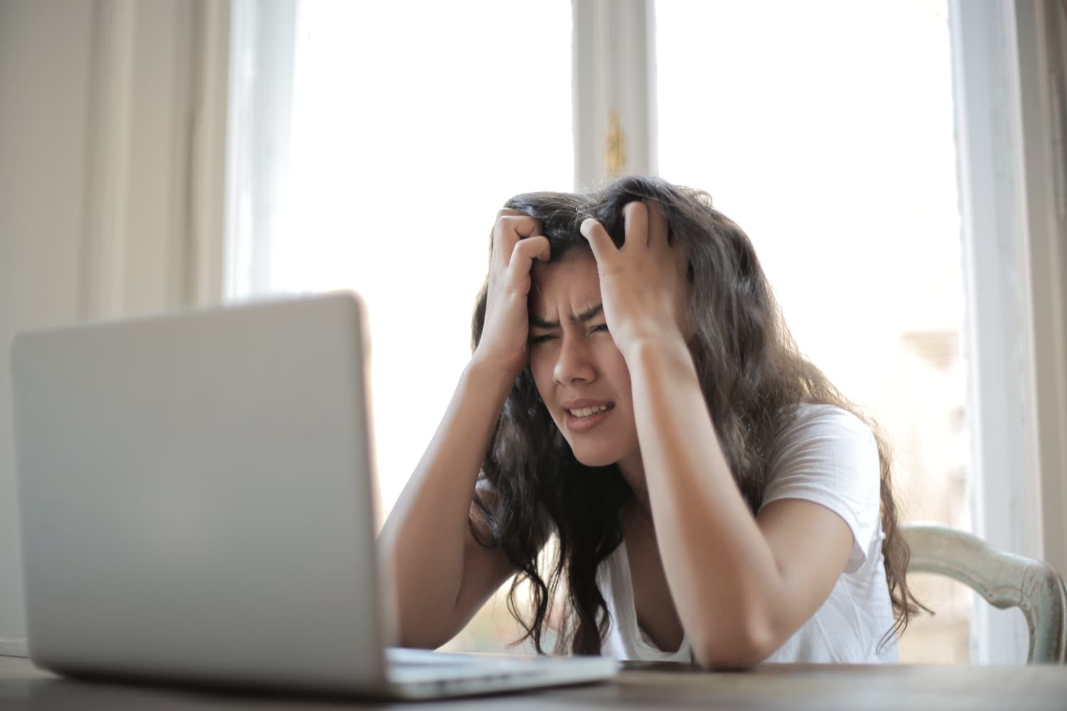 A woman is visibly frustrated in front of her computer.