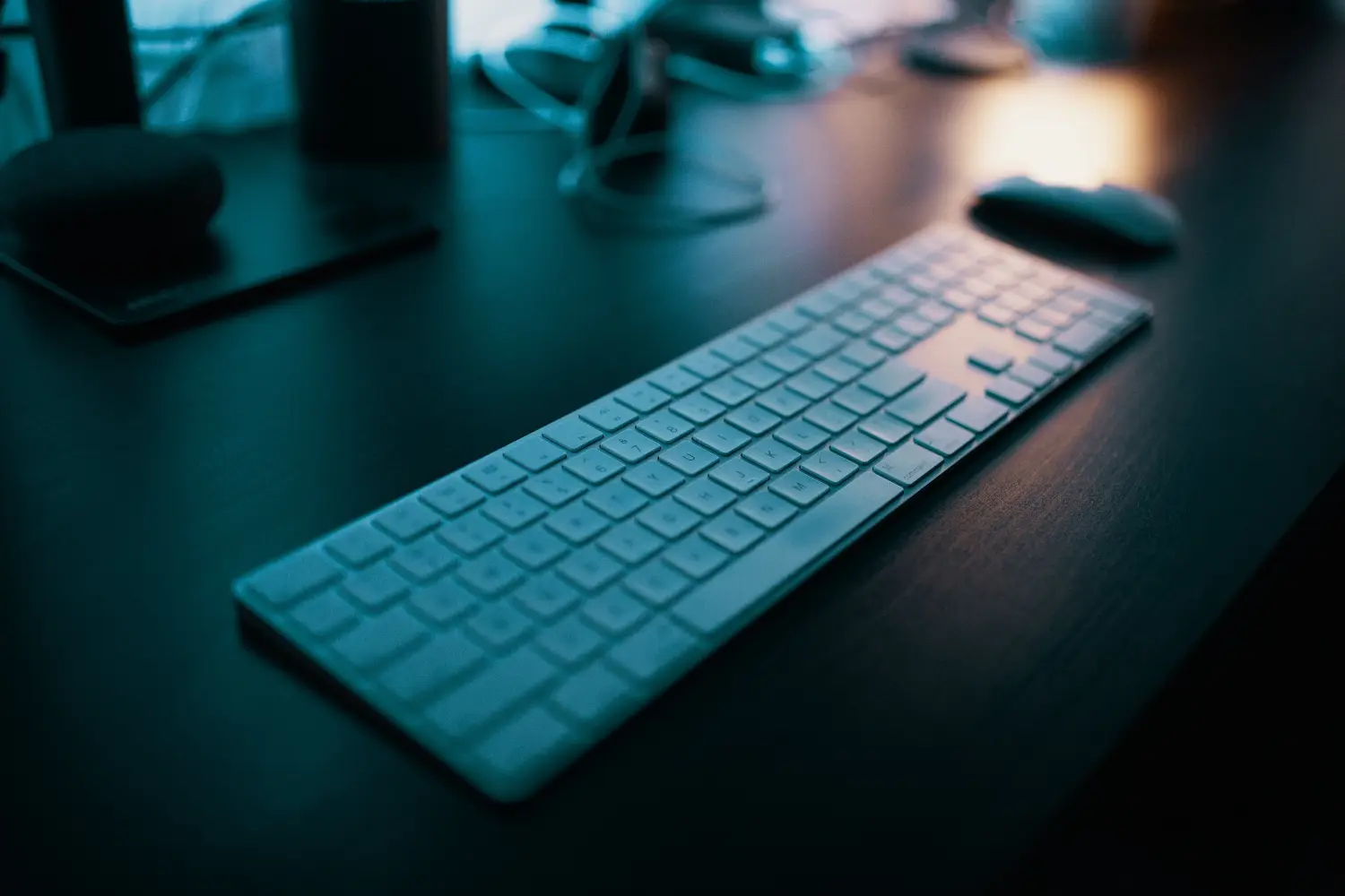 A computer keyboard and a mouse on a dark desk.